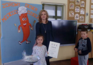 Dziewczynka z dyplomem i nagrodą pozuje do zdjęcia wraz z Panią Leśniak.